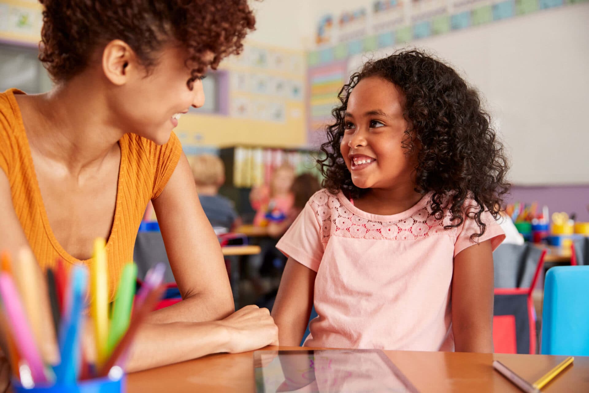 A teacher and a child smiling at each other in an Excel classroom