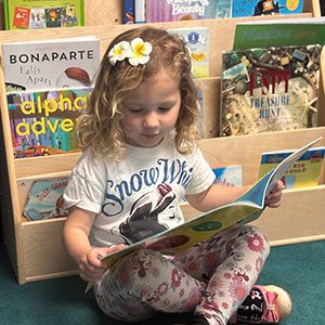 Preschool student reading a book in a classroom